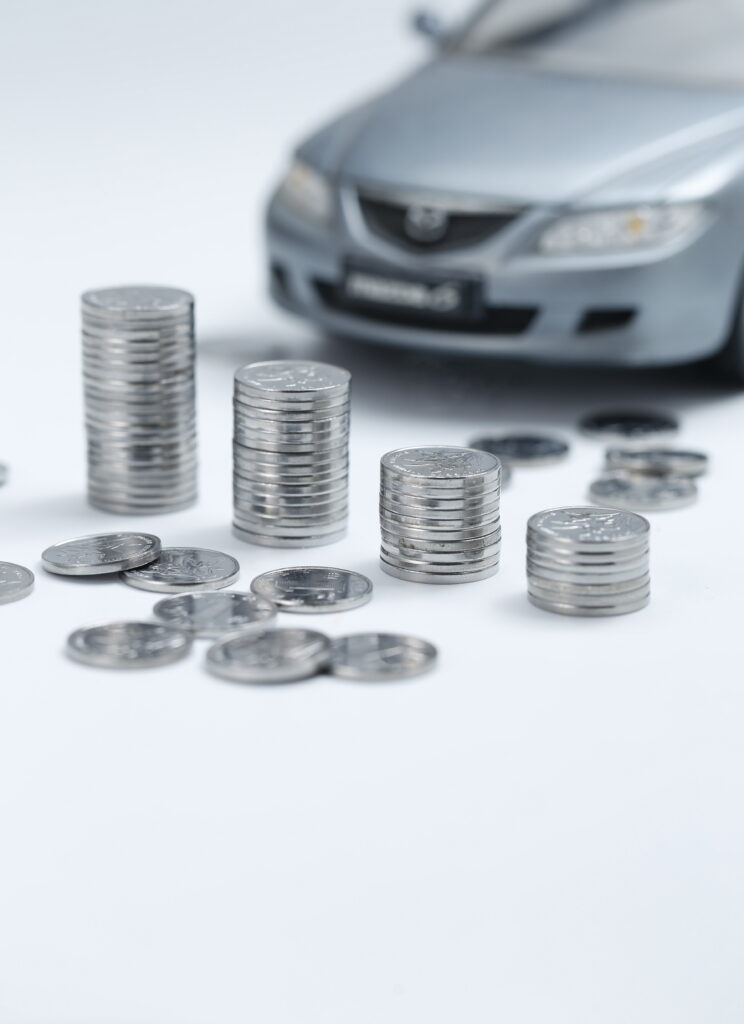 Stacks of coins in front of a car representing cash for junk cars in Edmonton